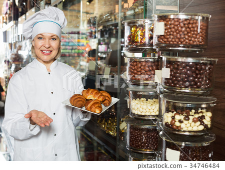 Elderly smiling seller with dark and white chocolates 34746484