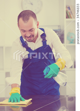 Young man in apron cleaning table Young man in apron cleaning table 34746833