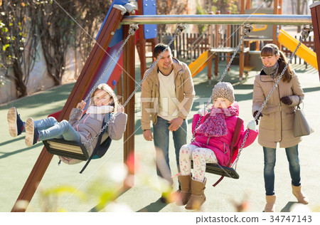 Positive family spending time at children swings 34747143