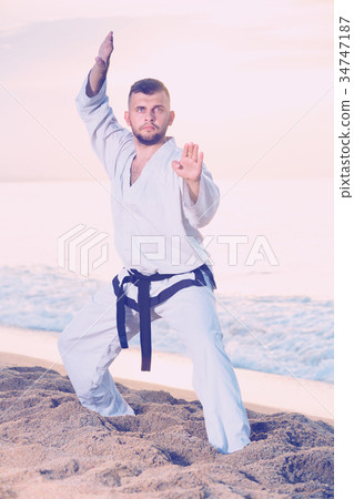 Guy doing karate poses at sunset sea shore 34747187