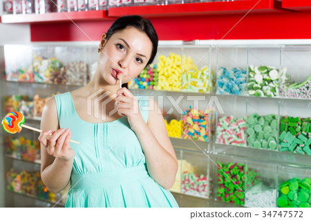 Smiling girl sucking lollypop in store Smiling girl sucking lollypop in store 34747572