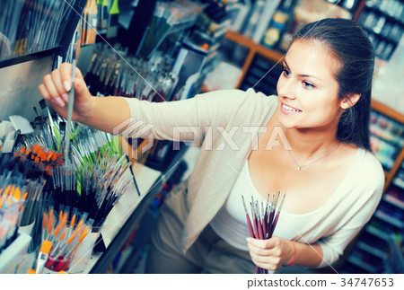 Pleased woman shopping various paintbrushes Pleased woman shopping various paintbrushes 34747653