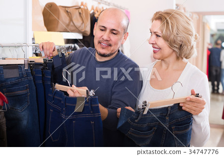 spouses buying pair of classic jeans in boutique spouses buying pair of classic jeans in boutique 34747776