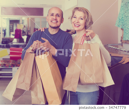 senior couple with purchases in bags at apparel store senior couple with purchases in bags at apparel store 34747779