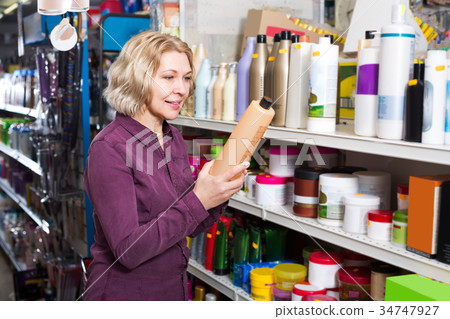 Mature woman selecting shampoo in store. Mature woman selecting shampoo in store. 34747927