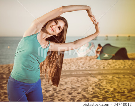 Portrait of sportswoman which is doing excercises for warm-up Portrait of sportswoman which is doing excercises for warm-up 34748012