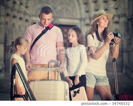 Parents travelling with children using camera and map 34748532
