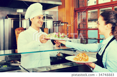 Happy professional chef and young waitress taking kebab for client 34748883
