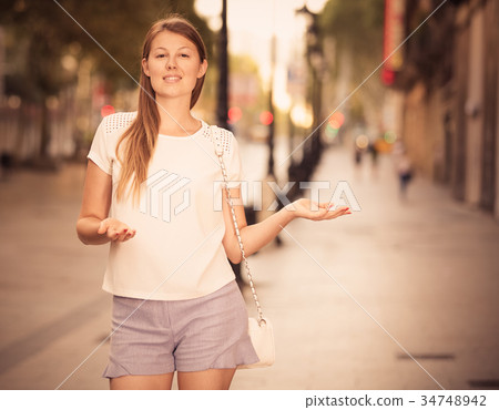 Young woman howing something on city street 34748942