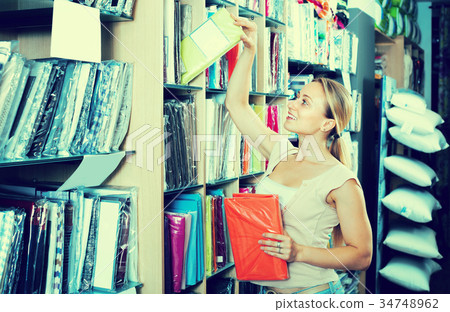 Woman picking bedding set in textile boutique Woman picking bedding set in textile boutique 34748962