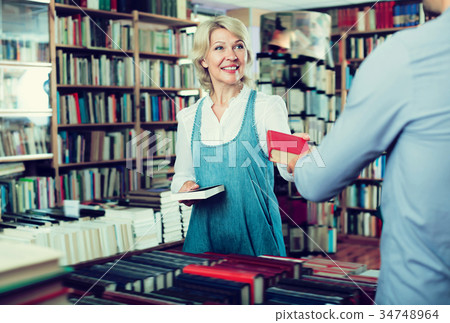 Adult woman taking book and talking to seller Adult woman taking book and talking to seller 34748964