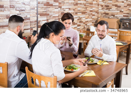 Smiling middle class people enjoying smartphones in cafe Smiling middle class people enjoying smartphones in cafe 34748965