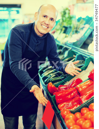 Salesman posing near different vegetables Salesman posing near different vegetables 34749477