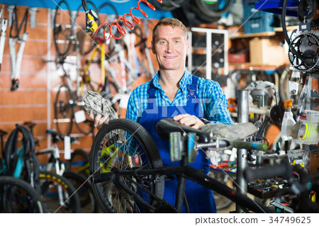 Smiling male seller in uniform picking bicycle 34749625
