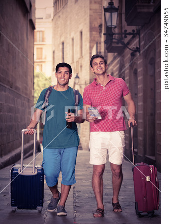 Two friends are walking with beer and watching 34749655