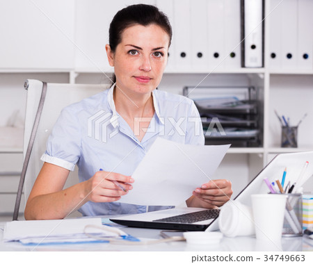 Thinking female in office sitting at the table 34749663