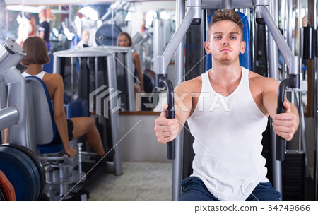 well trained man using pec deck gym machinery indoors 34749666