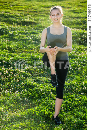 woman in sportwear doing exercises on mat in the garden 34749676