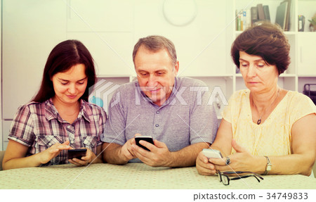 Mature parents with daughter sitting with phones Mature parents with daughter sitting with phones 34749833