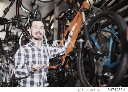 positive man in bicycle shop chooses for himself sports bike positive man in bicycle shop chooses for himself sports bike 34749834