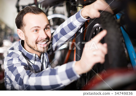 Man in sports workshop mounts bike using special tools Man in sports workshop mounts bike using special tools 34749836
