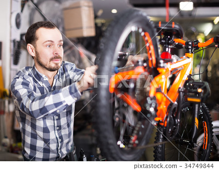 Man going to mount bicycle wheel 34749844