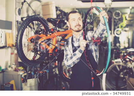 man in apron considering composition of wheel for bicycle 34749931