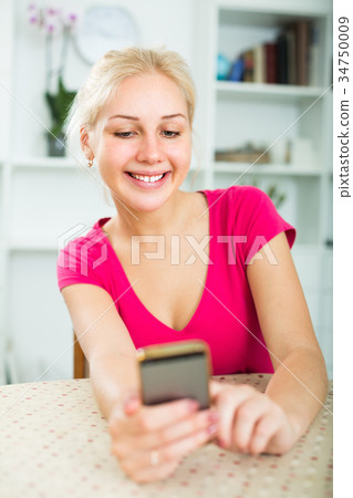 girl holding mobile phone at home. 34750009