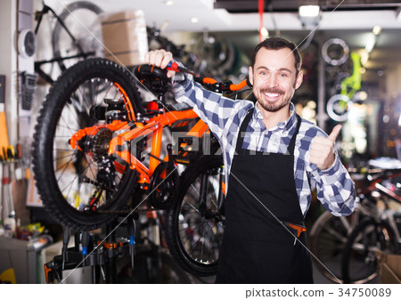 Mechanic in bicycles store workshop 34750089
