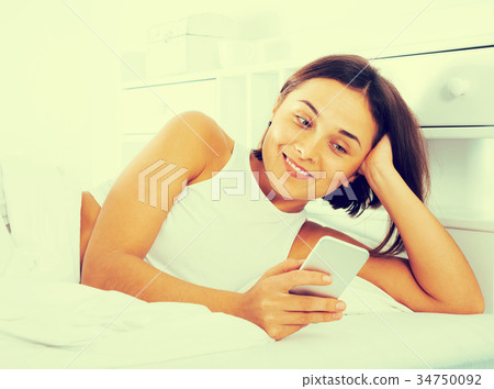 Woman using phone in bed 34750092