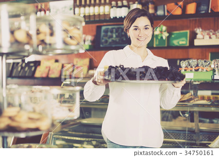 Seller offering tray of cakes 34750161