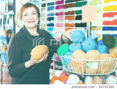 Mature woman choosing variety yarn for their hobby Mature woman choosing variety yarn for their hobby 34750360