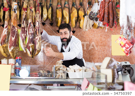 Laughing male seller showing jamon 34750397
