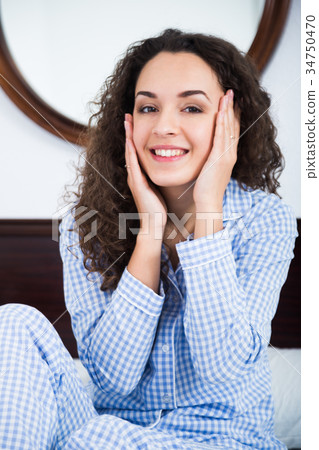 Girl sitting in bed and massaging face 34750470