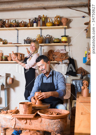 two potters working with ceramics in atelier. 34750627