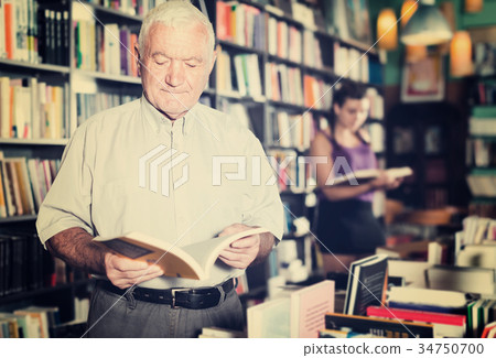 Old man customer is choosing book for reading Old man customer is choosing book for reading 34750700
