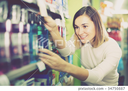 smiling girl customer looking for effective mouthwash in supermarket smiling girl customer looking for effective mouthwash in supermarket 34750887