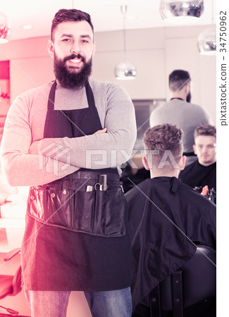 Young bearded guy displaying his workplace at hairdressing salon 34750962
