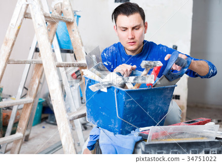 Man repairing room and looking for necessary tool Man repairing room and looking for necessary tool 34751022