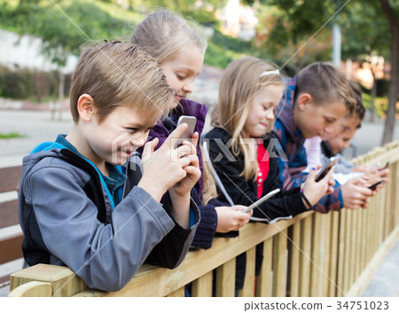 Outdoor portrait of girls and boys playing with phones Outdoor portrait of girls and boys playing with phones 34751023