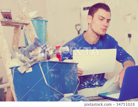 Male contractor working with papers and laptop Male contractor working with papers and laptop 34751028