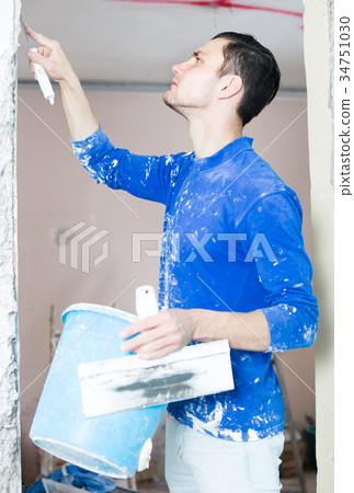 Plasterer renovating indoor doorway 34751030