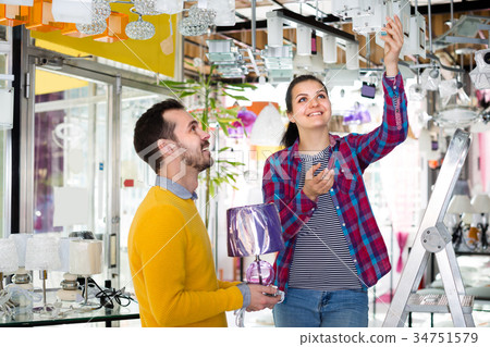 Female and male are choosing stylish and modern chandelier lamp. 34751579