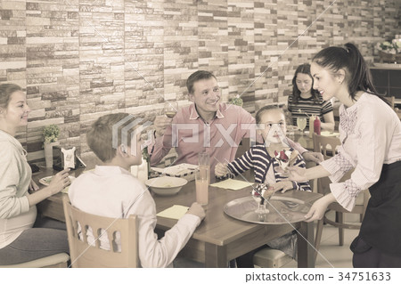 attentive brunette waitress serving family in family cafe attentive brunette waitress serving family in family cafe 34751633