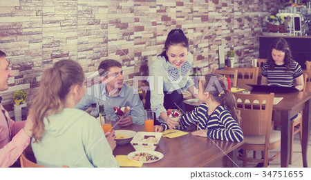 Polite attractive waitress serving dishes to family Polite attractive waitress serving dishes to family 34751655