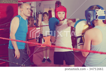 Teenage boy sportsman at boxing exercising with coach Teenage boy sportsman at boxing exercising with coach 34751661