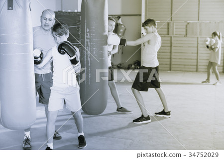 Boxing instructor and young children practicing blows Boxing instructor and young children practicing blows 34752029