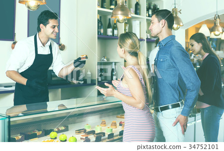 Seller helping friends to choose sweets Seller helping friends to choose sweets 34752101