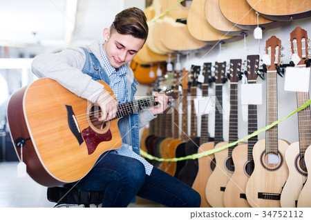Young boy is choosing quality acoustic guitar Young boy is choosing quality acoustic guitar 34752112