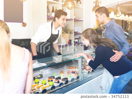 Family couple with female friend are choosing delicious cakes from showcase Family couple with female friend are choosing delicious cakes from showcase 34752113